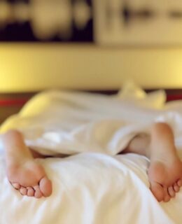 Person sover i sin seng med fødderne der stikker ud